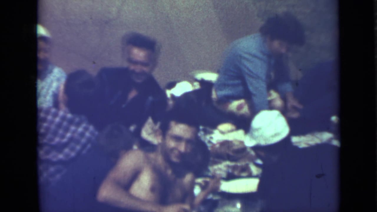 1967 Saint Petersburg home-movie frame showing people gathered outdoors around picnic plates and food.
