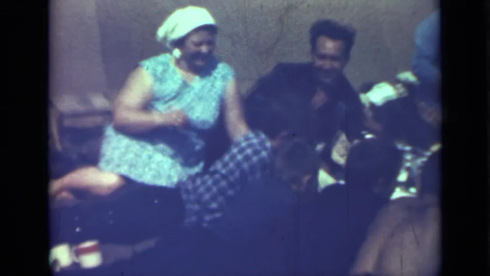 1967 Saint Petersburg 8mm frame of a woman in a headscarf seated with others during an outdoor picnic.