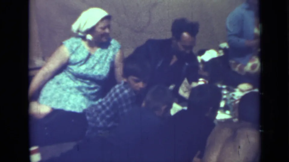 1967 Saint Petersburg home-movie frame of adults seated on the ground during a picnic meal.