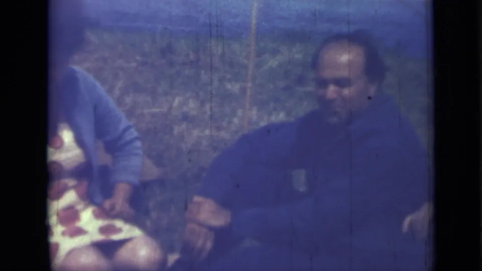 1967 Saint Petersburg frame showing a man seated in a grassy field beside a partially visible woman during a picnic scene.