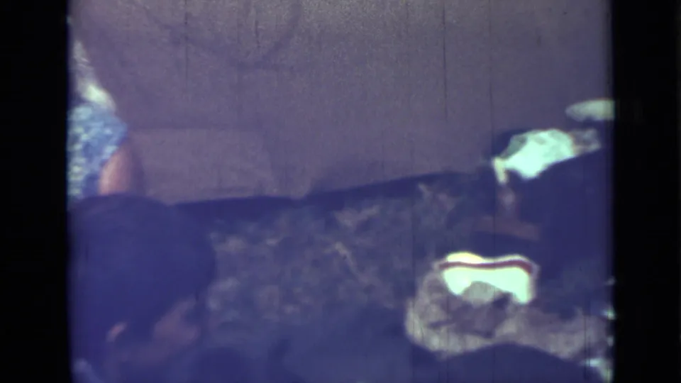 Home-movie frame from the Saint Petersburg clip showing adults seated close together during an informal meal setting.