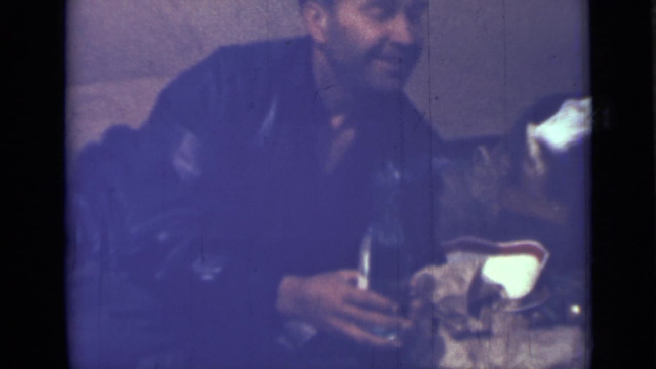 Seated man turns while holding a bottle near another person.