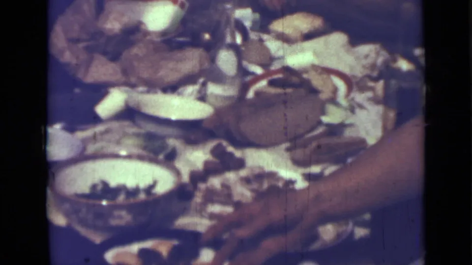 1967 Saint Petersburg picnic frame showing a basket, bread, dishes, bowl, dark bottle, and an adult arm near the table edge.