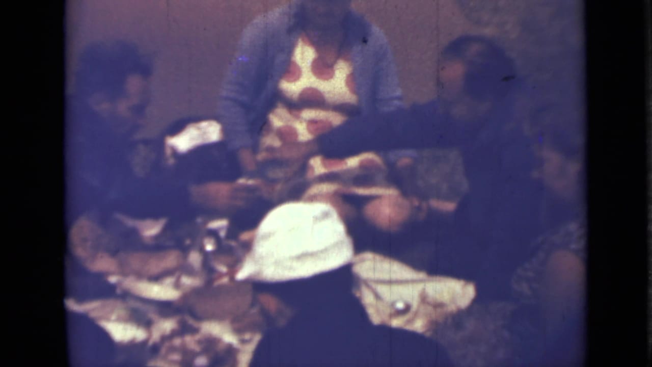 1967 Saint Petersburg home-movie frame of adults eating and talking around a table in a private interior.
