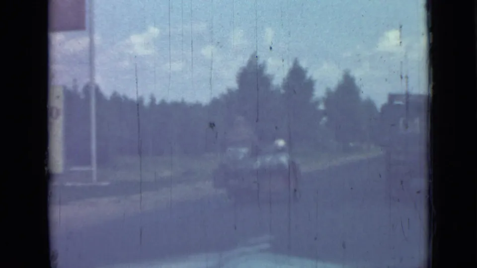 1967 Saint Petersburg home-movie frame with a soft, blue-tinted moving-road view after the indoor gathering.