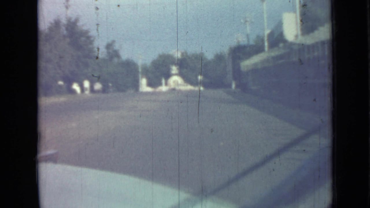 Soft car-window view down a broad street toward a distant white monument and trees.
