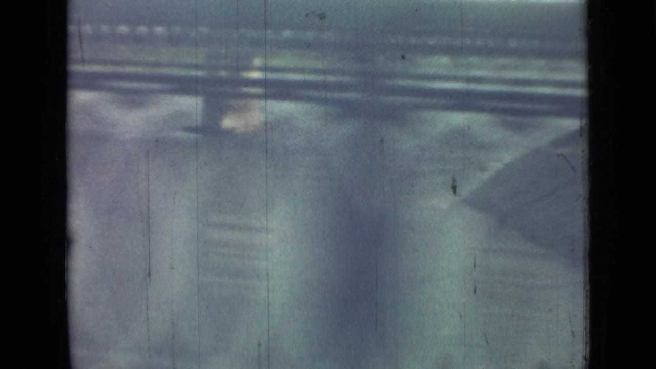Obstructed moving view with dark window edges, blurred pavement, and horizontal lines.