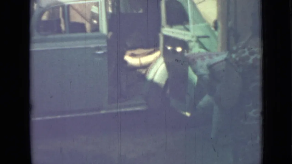 A person in a patterned dress approaches the open rear door of a blue van in the supplied 1967 Saint Petersburg footage.
