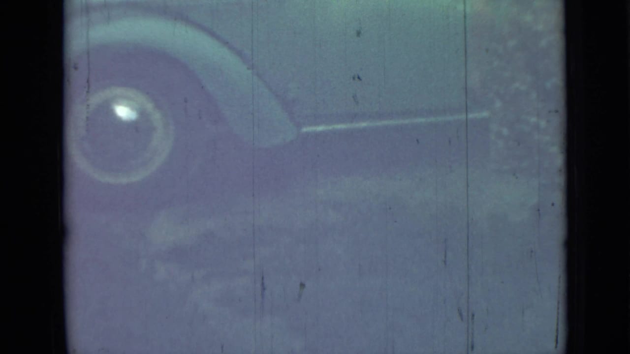 Faded view of a vintage car side with a rounded fender and wheel.