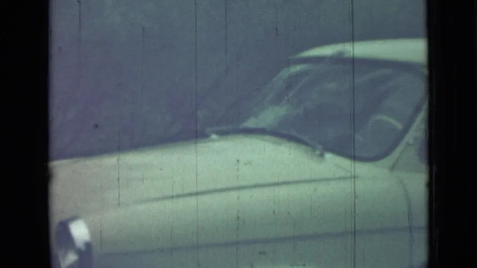 1967 Saint Petersburg 8mm frame showing the side and windshield of a pale classic car under heavy grain and muted color.