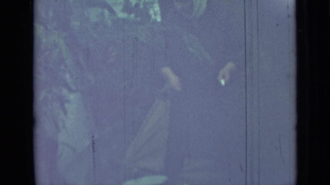 Faded campsite frame with a partial person and tent fabric near dark film borders.