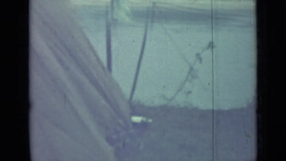 The frame shows pale canvas tent fabric and dark poles or lines at the Saint Petersburg campsite, with soft 8mm grain and color fading.