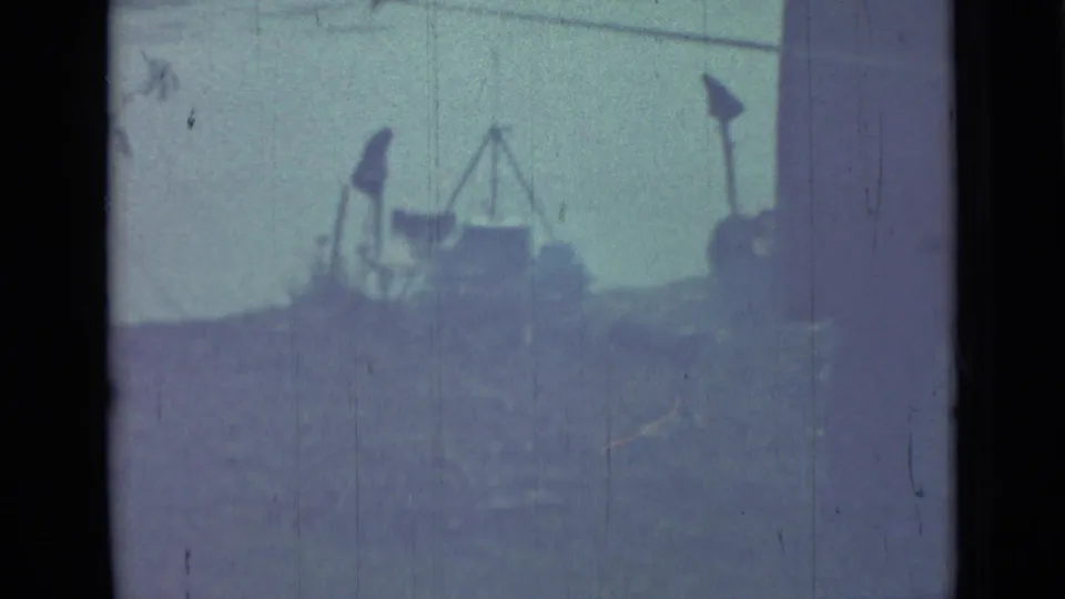 1967 Saint Petersburg 8mm frame showing a grassy outdoor area with tripod-like equipment and a pale waterside background.