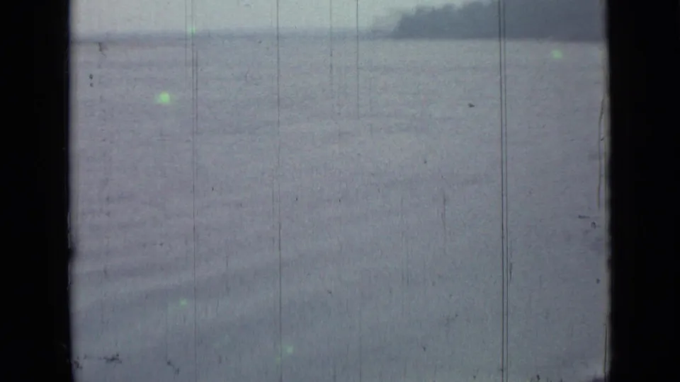 A hazy lake or pond view, associated with 1967 Saint Petersburg metadata, shows water, distant shore, and aged 8mm film texture.