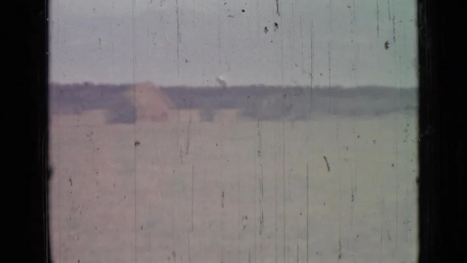 1967 8mm countryside view near Saint Petersburg with a pale field, distant mound, low horizon, and visible film wear.