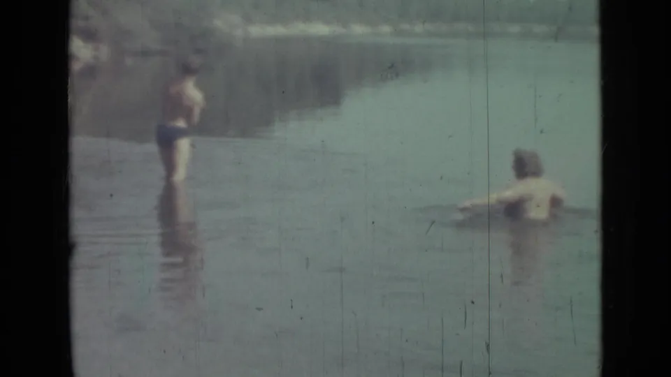 Saint Petersburg 1967 8mm frame with two young people in shallow water, one standing near center and another partly submerged at right.