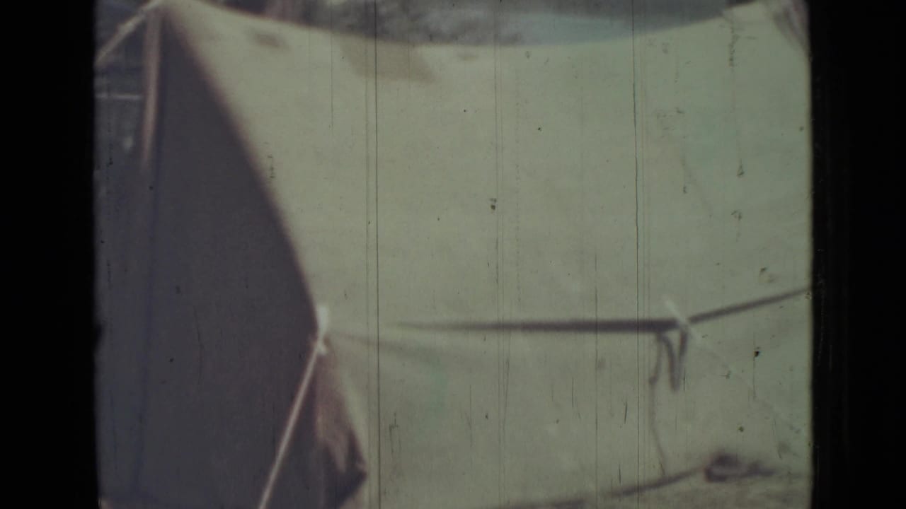 1967 8mm frame from Saint Petersburg metadata showing a close, soft-focus view of a green tent side with line and pole.