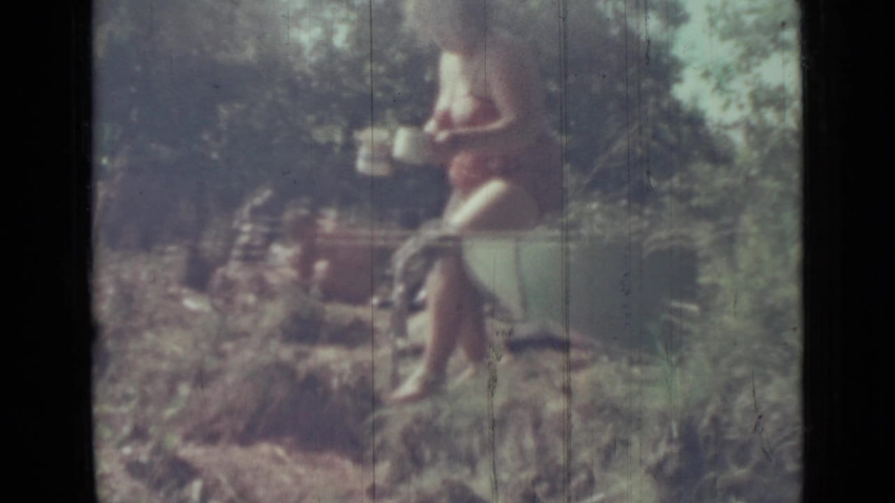 Woman in a red bikini holding a white container in a wooded area.