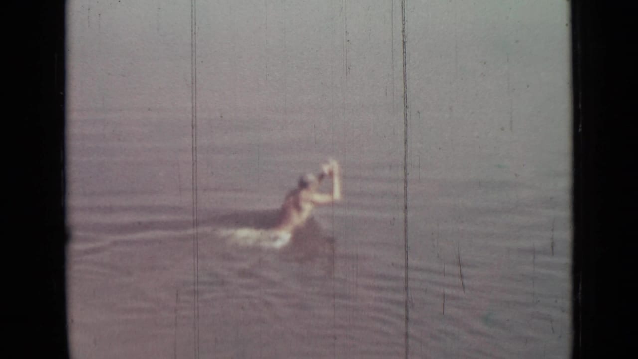 Boy splashing forward in calm open water.