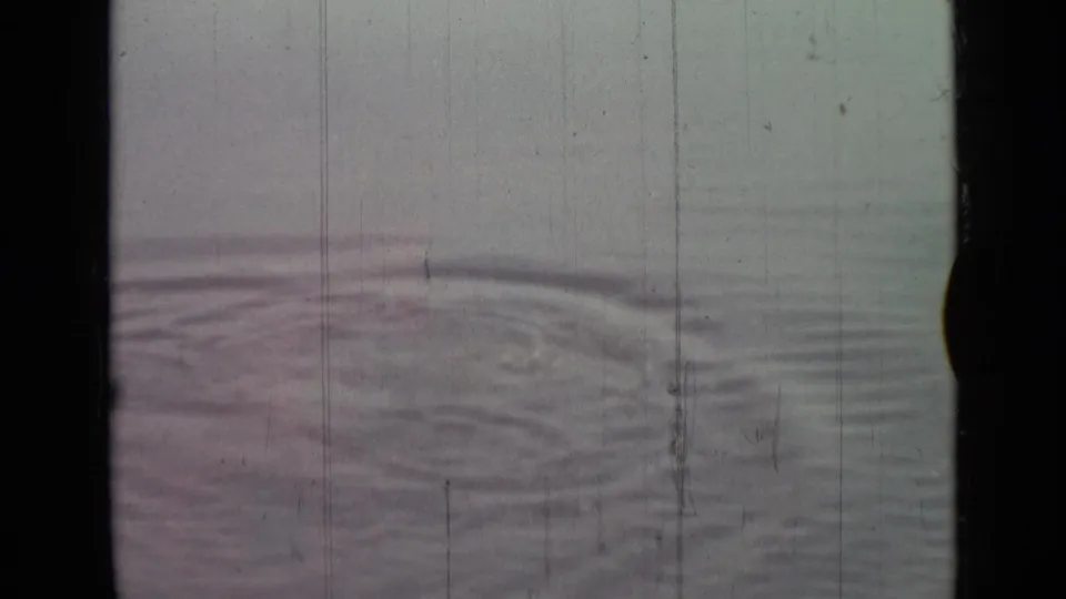 1967 8mm frame from Saint Petersburg metadata showing circular water disturbance, haze, scratches, and faded color.