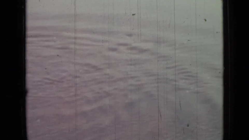 1967 Saint Petersburg 8mm frame of still rippling water, with muted pink-gray tones and visible physical film wear.
