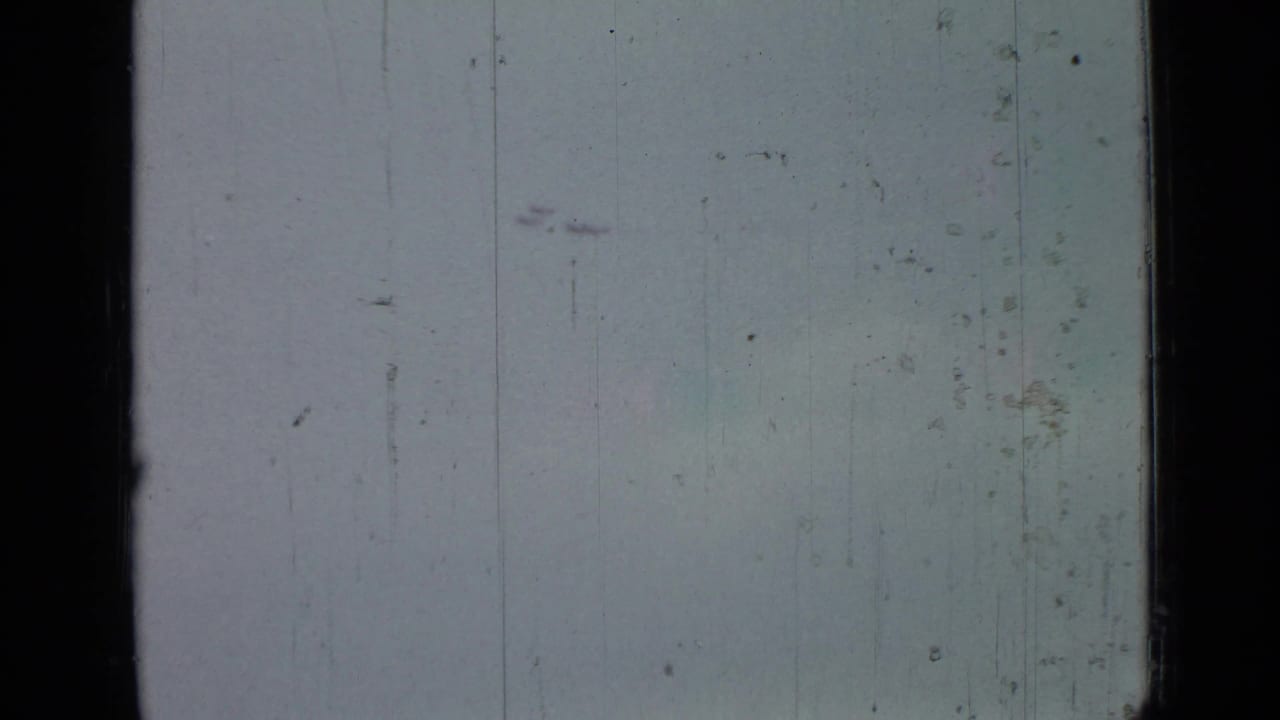 Mostly pale sky with faint distant aircraft marks and heavy 8mm film edges.