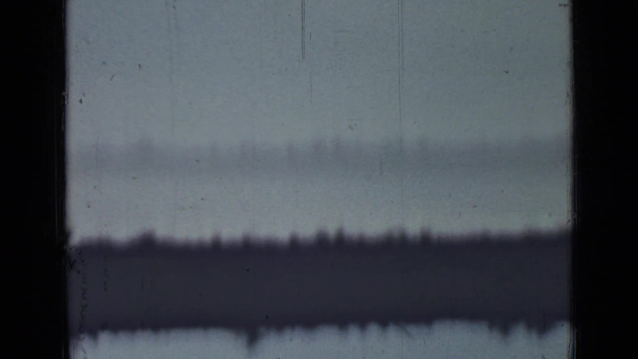 1967 Saint Petersburg metadata frame showing a pale overexposed sky, black 8mm frame borders, surface scratches, and a distant dark horizon-like band.