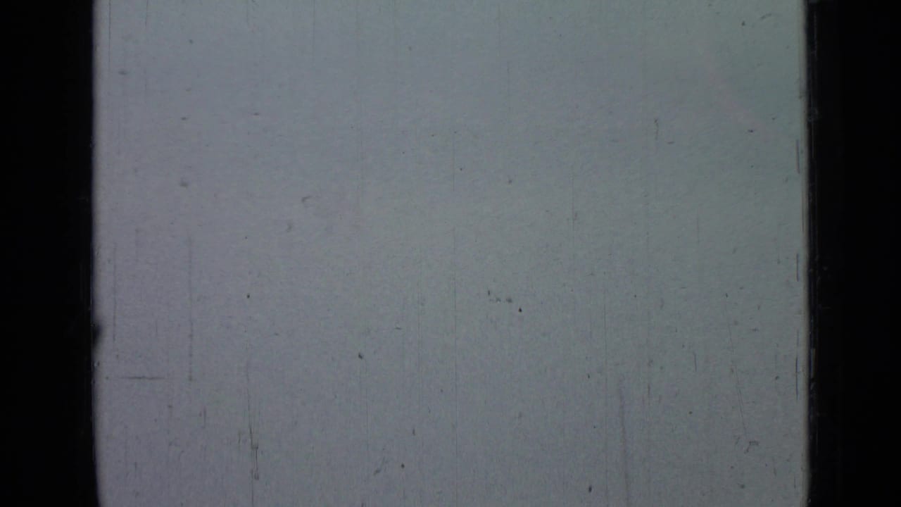 Pale gray-blue sky from the supplied 1967 Saint Petersburg home-movie metadata, bordered by dark film edges with visible dust, scratches, and color fading.