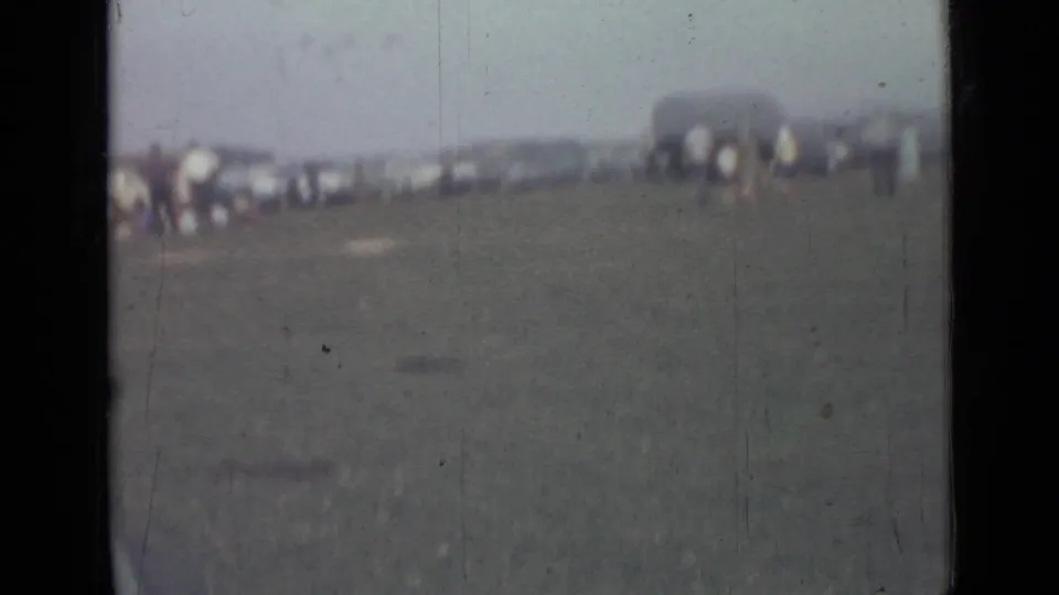 1967 Saint Petersburg home-movie frame showing distant people on grass near a dark arched structure in hazy soft focus.