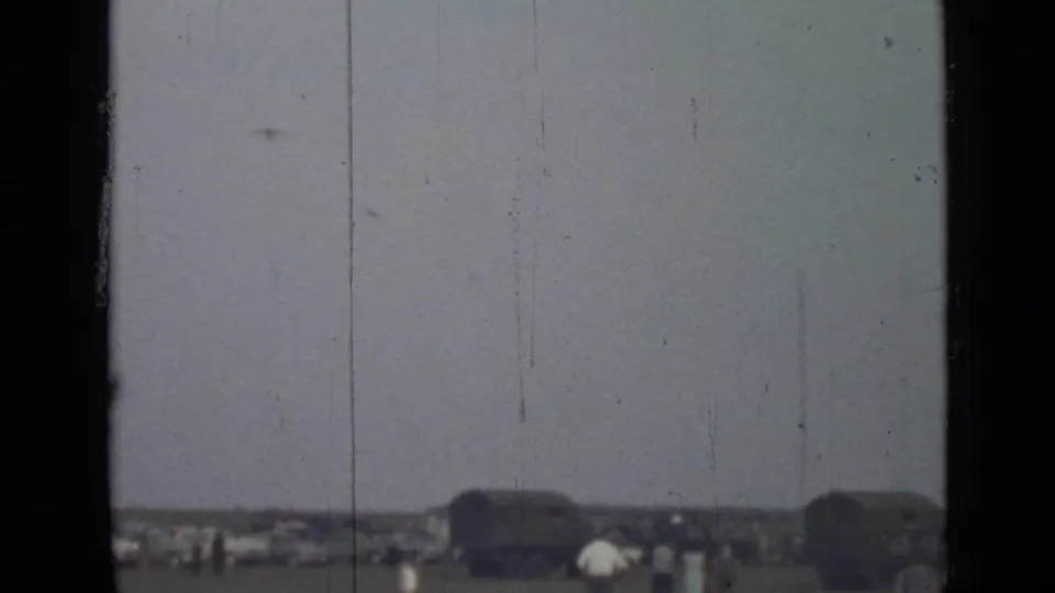 Final 1967 Saint Petersburg frame with tiny figures near dark vehicle-like structures, heavy sky, film scratches, and a black vertical frame edge.