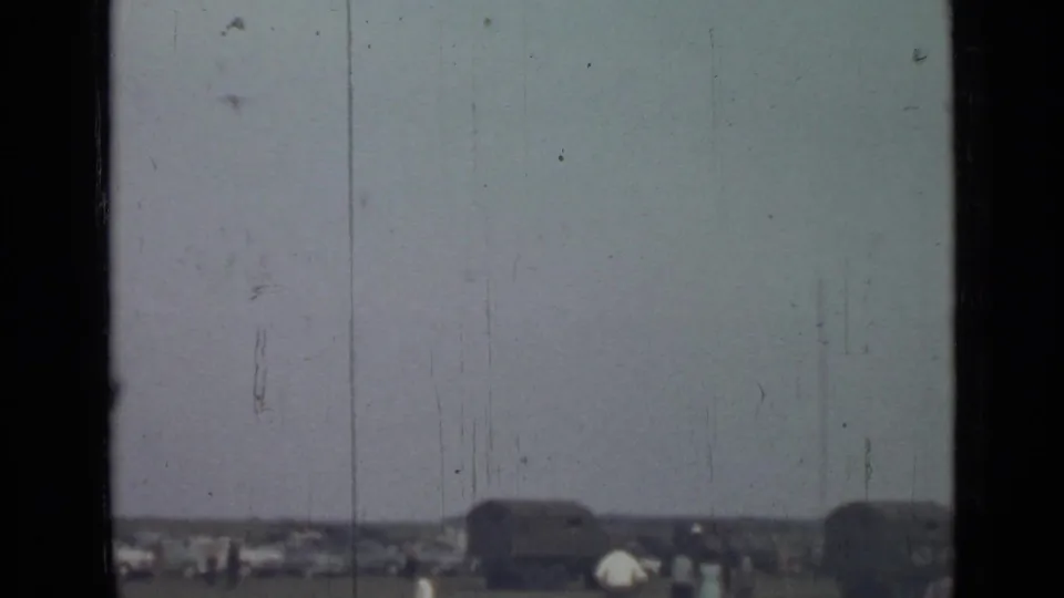 1967 Saint Petersburg home-movie frame with a pale sky, distant field activity, and dark window framing across the view.