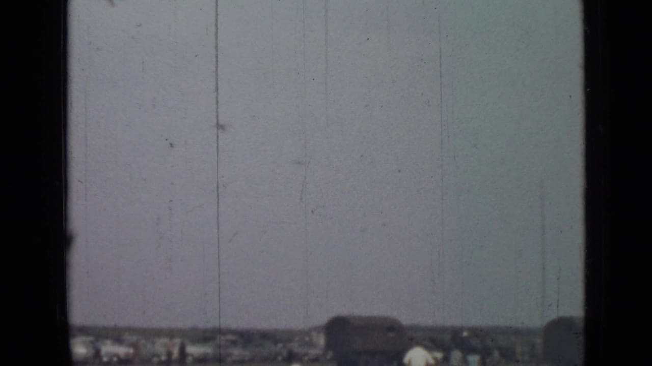 Distant open field under a pale sky, partly divided by a dark vertical window frame.