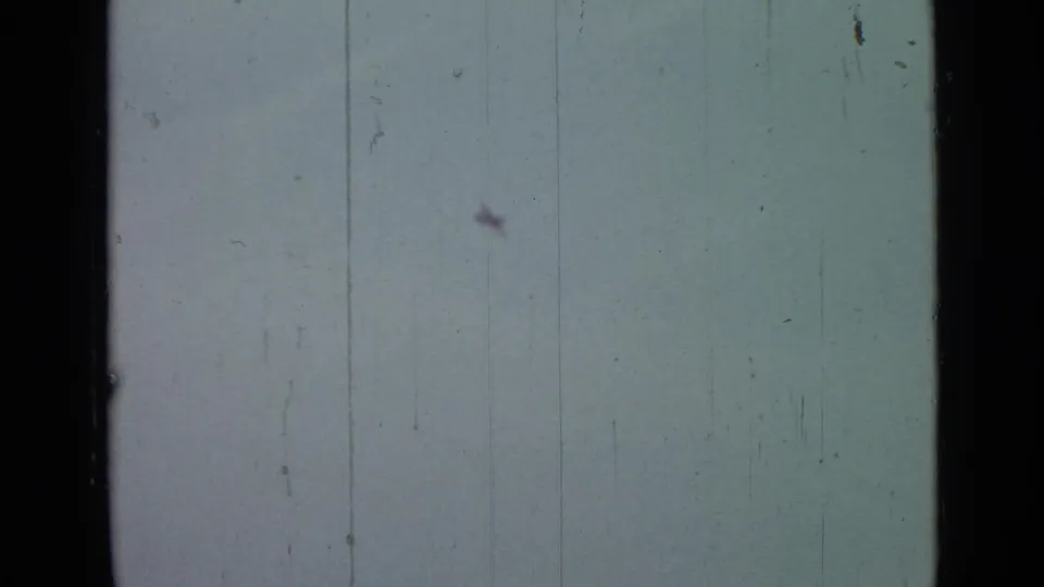 Cloudy sky fills the frame, with the aircraft difficult to distinguish and 8mm wear marks visible.