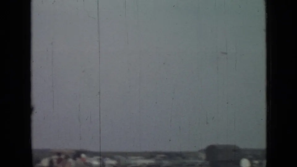 Soft 1967 8mm frame from Saint Petersburg metadata showing pale sky, low distant structures, and dark vertical gate borders.