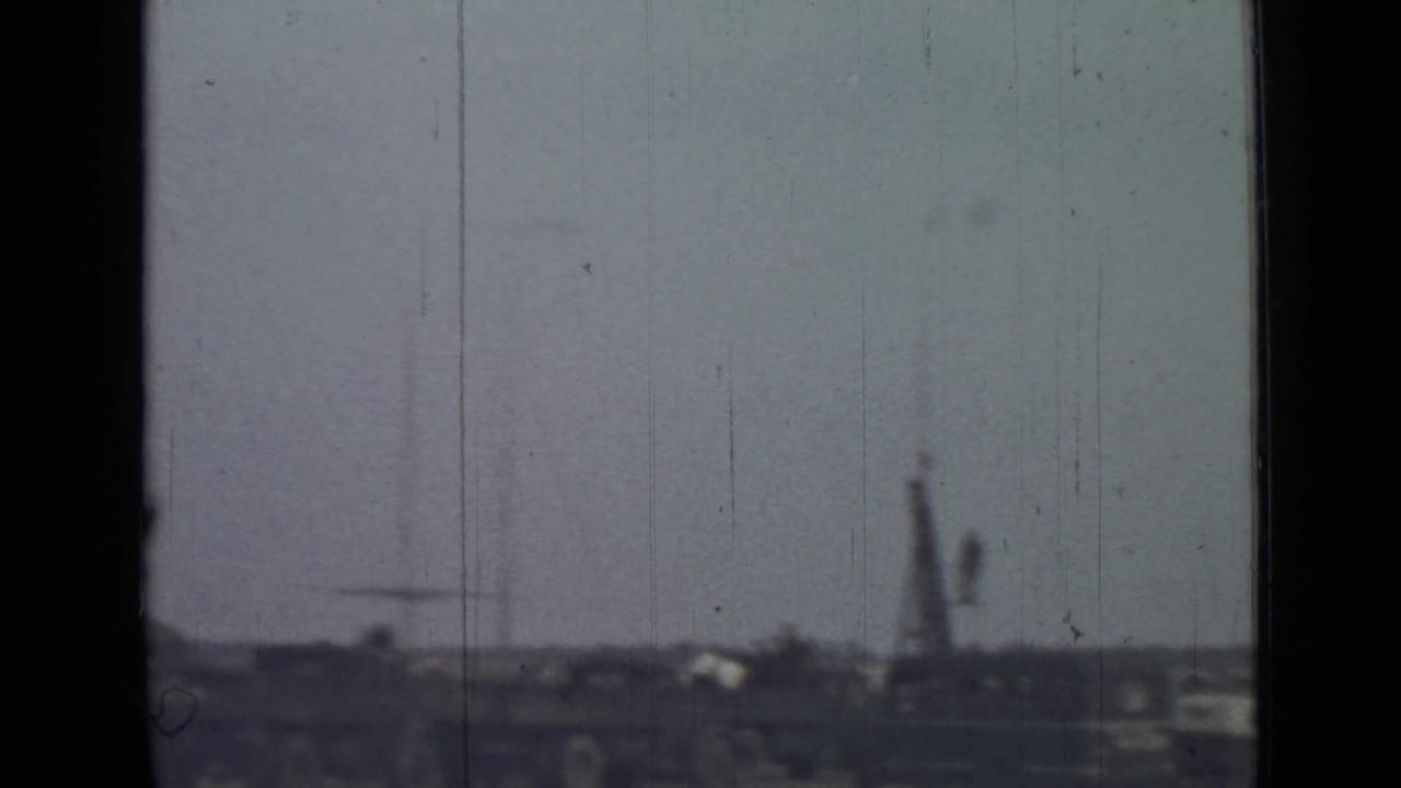 Distant field edge with low structures and a tall indistinct vertical form.