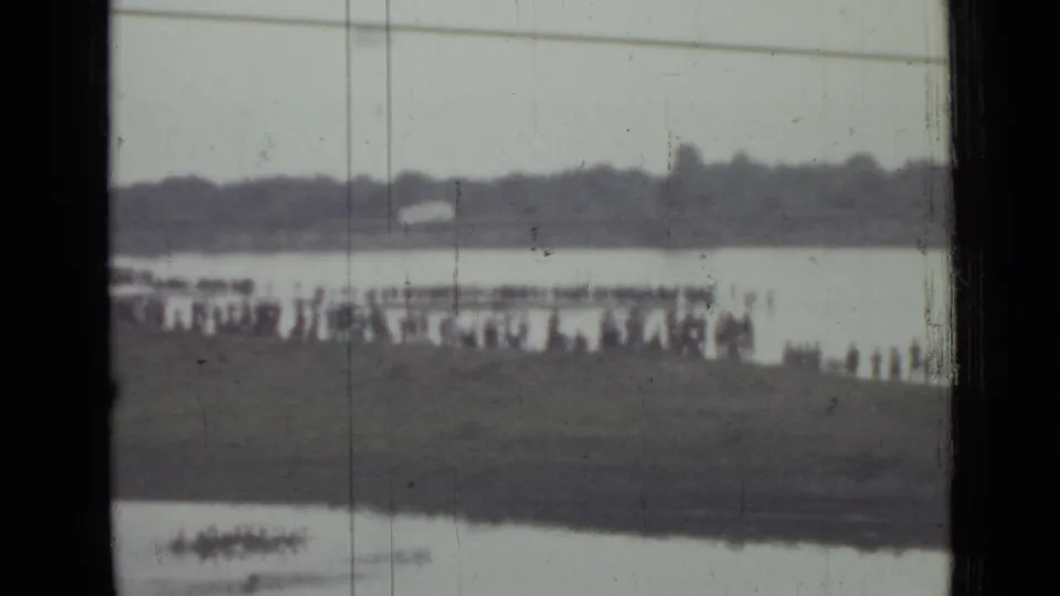Final 8mm frame shows spectators near the water in Saint Petersburg, with a small pale shape near the far bank that may be the parachute after landing.