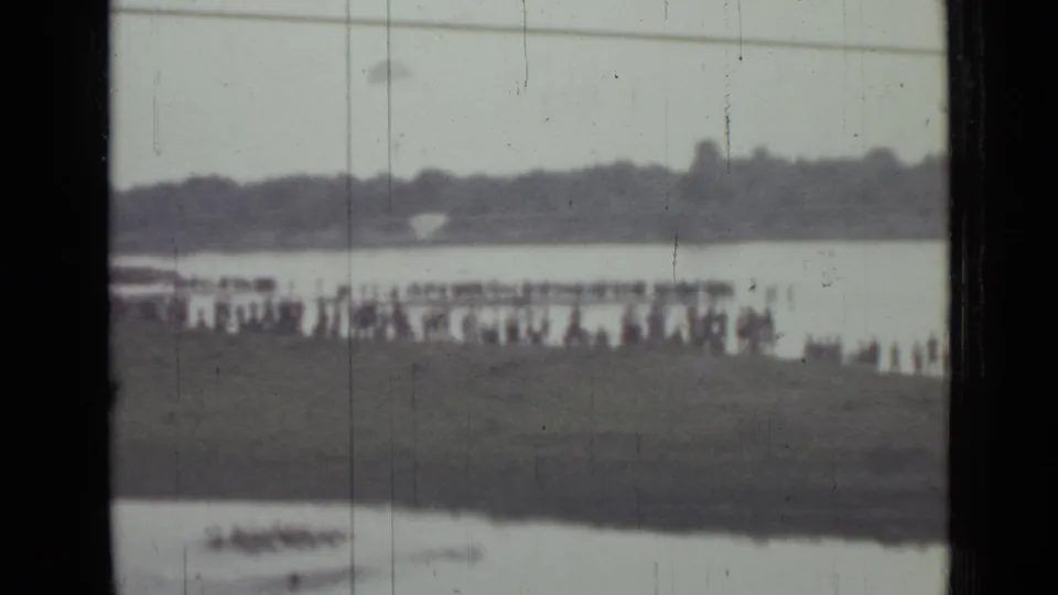 1967 8mm view in Saint Petersburg showing a distant lakeside crowd, open water, and a small boat near the lower edge of frame.