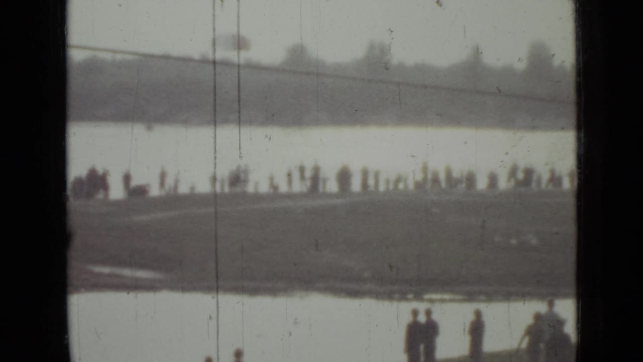 Soft 1967 Saint Petersburg lakeside frame showing a long line of distant spectators and a few closer figures near the bottom edge.