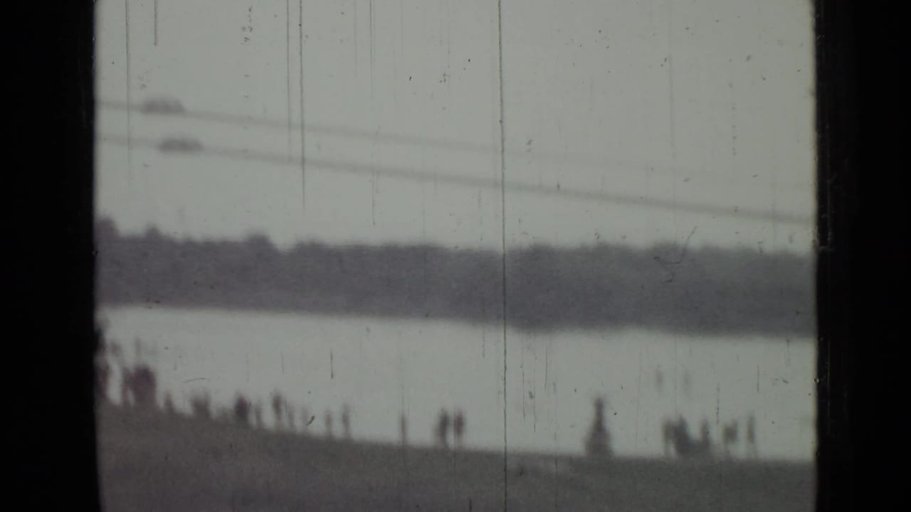 A red parachute-like object appears over the Saint Petersburg waterway as distant spectators watch from the shoreline.