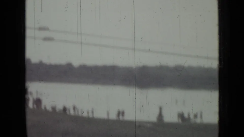 A red parachute-like object appears over the Saint Petersburg waterway as distant spectators watch from the shoreline.
