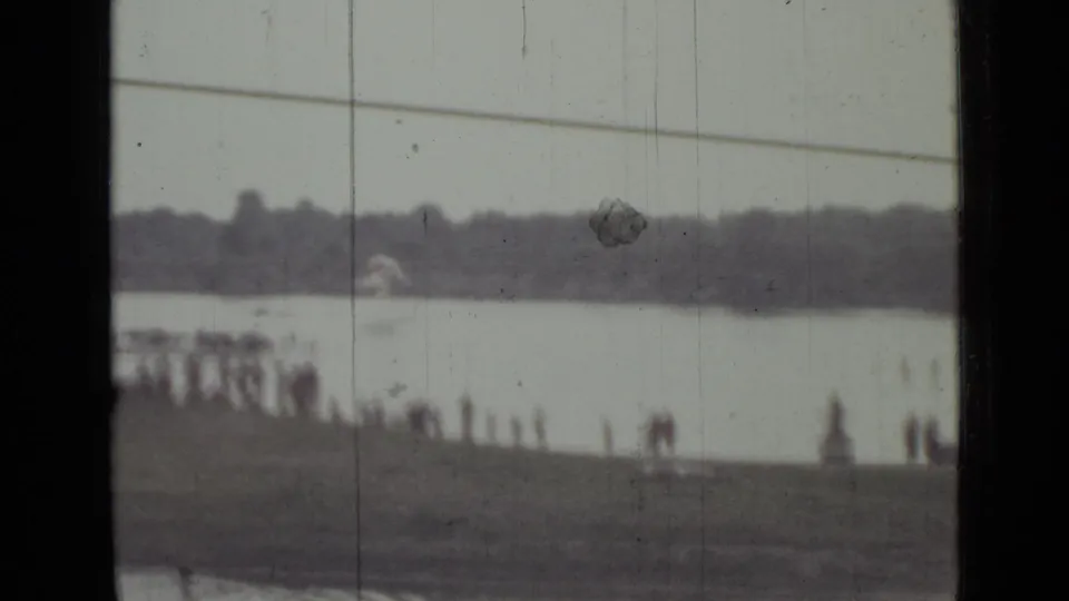 1967 8mm footage near Saint Petersburg showing a distant lakeshore, treeline, and small spectator figures along the water.