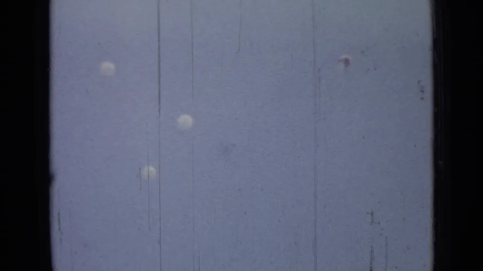 Parachutes drift downward above a faint lakeshore horizon in the Saint Petersburg 1967 home-movie scene.