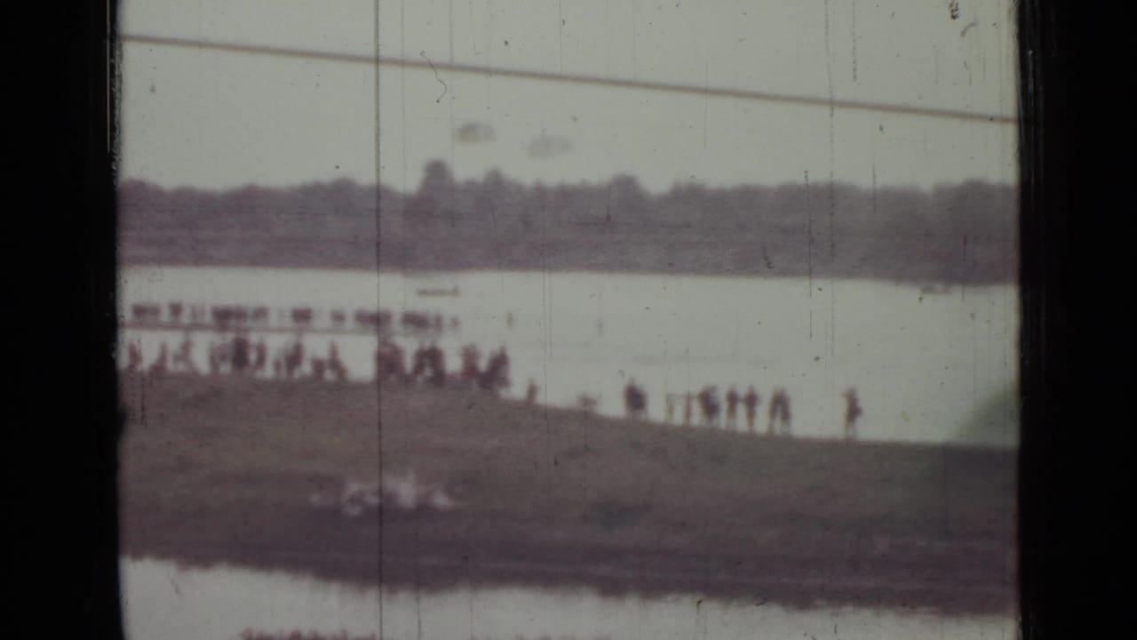 1967 Saint Petersburg 8mm frame with silhouetted spectators along a low bank and indistinct shapes near the waterline.
