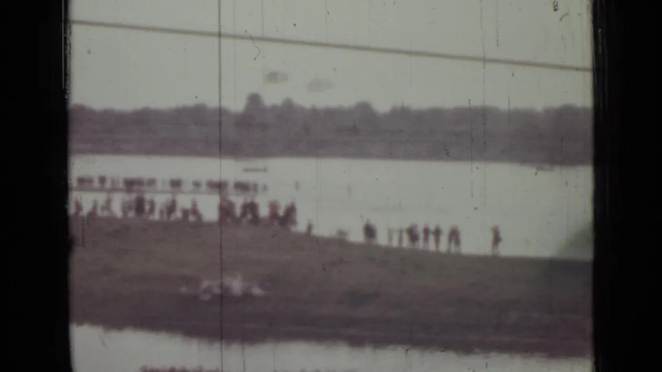 1967 Saint Petersburg 8mm frame with silhouetted spectators along a low bank and indistinct shapes near the waterline.