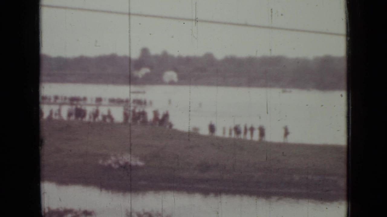 Final 1967 Saint Petersburg frame with small silhouetted people along the shore, a wide water surface, and aged film texture.