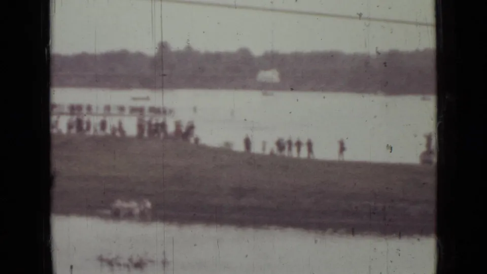 1967 Saint Petersburg 8mm frame with distant spectators on the shore and a pale parachute shape across the river.