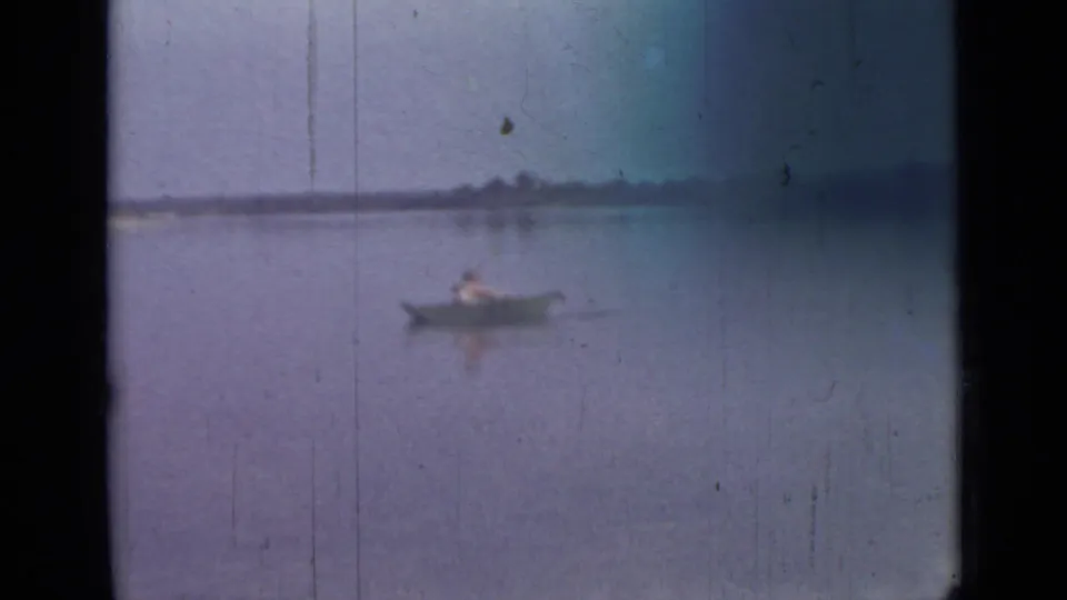 1967 Saint Petersburg home-movie frame showing a lone rower crossing a quiet lake in soft focus.