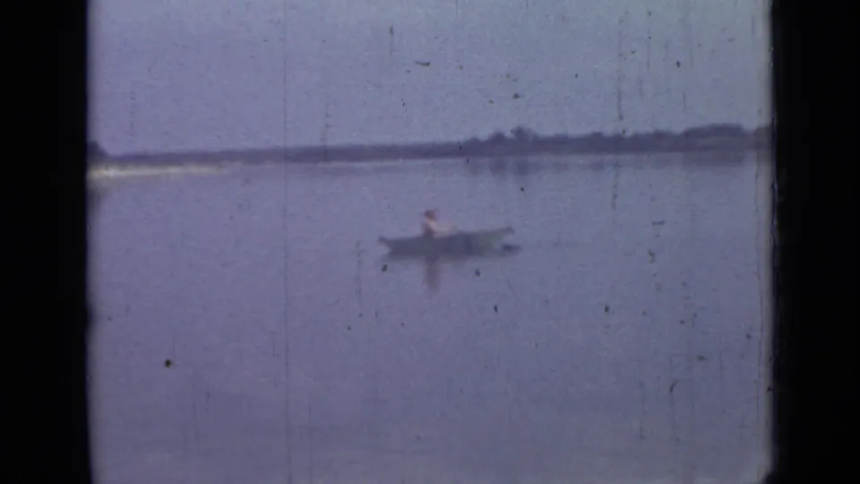 1967 Saint Petersburg lakeside frame with a lone rower in a small boat against a distant shoreline.