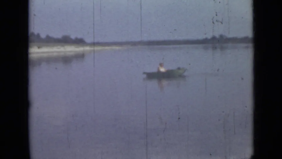 A lone canoeist appears in a small boat on calm water in 1967 Saint Petersburg footage, with a pale bank across the horizon.