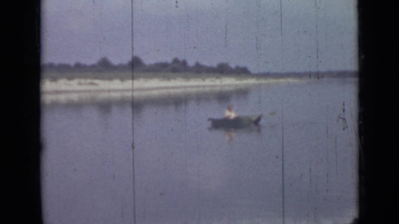 A distant person rows a small boat on calm water in this soft 1967 Saint Petersburg home-movie frame.